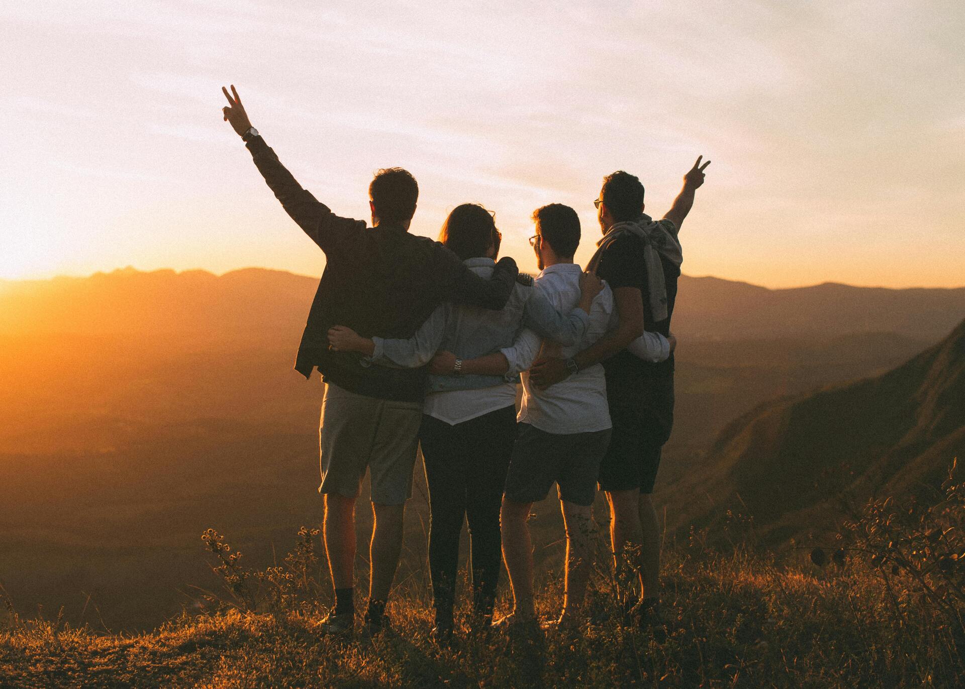 Grupo de amigos celebrando un atardecer en la montaña